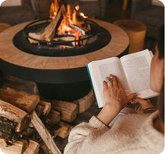 woman reading a book by a fire pit